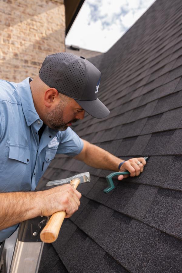 Robert Spence repairing shingles on a roof